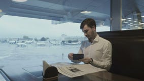 El hombre de negocios atractivo mira su documento de embarque en el aeropuerto metrajes El hombre de negocios atractivo mira su documento de embarque en el aeropuerto metrajes