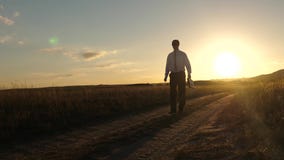 El hombre de negocios en gafas de sol va abajo de la carretera nacional con una cartera en su mano Concepto agr?cola del negocio almacen de video El hombre de negocios en gafas de sol va abajo de la carretera nacional con una cartera en su mano Concepto agr?cola del negocio almacen de video