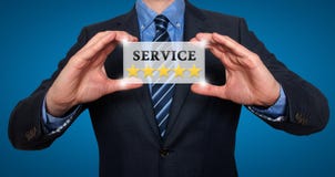 El hombre de negocios que sostiene la tarjeta blanca con las estrellas del servicio cinco firma, azul imagenes de archivo El hombre de negocios que sostiene la tarjeta blanca con las estrellas del servicio cinco firma, azul imagenes de archivo