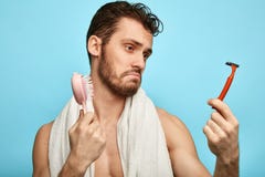 El hombre decepcionado vacilado confundido mira la m?quina de afeitar a disposici?n fotografía de archivo El hombre decepcionado vacilado confundido mira la m?quina de afeitar a disposici?n fotografía de archivo