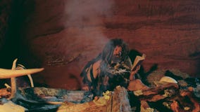 El hombre del Neanderthal lee el libro viejo cerca de hoguera en su cueva almacen de video El hombre del Neanderthal lee el libro viejo cerca de hoguera en su cueva almacen de video