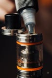 El hombre en una tienda del vape está llenando un líquido especial en e-cigarrillo fotografía de archivo libre de regalías El hombre en una tienda del vape está llenando un líquido especial en e-cigarrillo fotografía de archivo libre de regalías