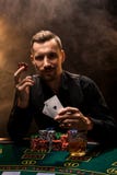 El hombre está jugando el póker con un cigarro y un whisky, tarjetas de una demostración dos del hombre en la mano, ganando todos imágenes de archivo libres de regalías El hombre está jugando el póker con un cigarro y un whisky, tarjetas de una demostración dos del hombre en la mano, ganando todos imágenes de archivo libres de regalías