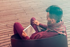 El hombre joven elegante trabaja en la tableta al aire libre en espacio público urbano imágenes de archivo libres de regalías El hombre joven elegante trabaja en la tableta al aire libre en espacio público urbano imágenes de archivo libres de regalías