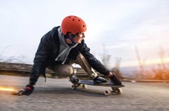 El hombre joven en casco va a resbalar, resbalar con las chispas en un longboard en el asfalto Foto de archivo El hombre joven en casco va a resbalar, resbalar con las chispas en un longboard en el asfalto Foto de archivo