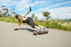 El hombre joven en casco va a resbalar, resbalar con las chispas en un longboard en el asfalto Foto de archivo libre de regalías El hombre joven en casco va a resbalar, resbalar con las chispas en un longboard en el asfalto Foto de archivo libre de regalías