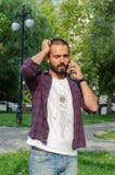 El hombre joven está hablando en su teléfono celular en el parque fotos de archivo libres de regalías El hombre joven está hablando en su teléfono celular en el parque fotos de archivo libres de regalías