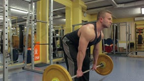 El hombre muscular levanta un barbell pesado en un gimnasio almacen de video El hombre muscular levanta un barbell pesado en un gimnasio almacen de video