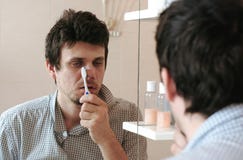 El hombre soñoliento cansado con una resaca que acaba de despertar el cepillo sus dientes, mira su reflexión en el espejo imagen de archivo El hombre soñoliento cansado con una resaca que acaba de despertar el cepillo sus dientes, mira su reflexión en el espejo imagen de archivo