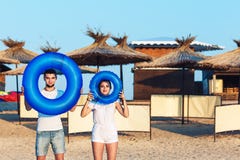 El hombre y la mujer están presentando en la playa y están llevando a cabo círculos inflables concepto de día de fiesta del mar d foto de archivo libre de regalías El hombre y la mujer están presentando en la playa y están llevando a cabo círculos inflables concepto de día de fiesta del mar d foto de archivo libre de regalías