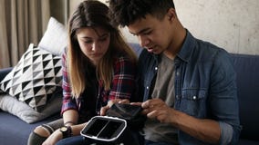 El individuo hermoso joven del mulato inserta un cierto detalle en las VR-auriculares Su novia caucásica se está sentando al lado almacen de video El individuo hermoso joven del mulato inserta un cierto detalle en las VR-auriculares Su novia caucásica se está sentando al lado almacen de video