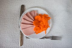El jamón cortado con las zanahorias está en la placa fotografía de archivo El jamón cortado con las zanahorias está en la placa fotografía de archivo
