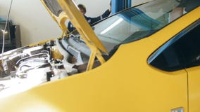 El mecánico levanta el coche amarillo en el servicio del automóvil del garaje - pequeña empresa metrajes El mecánico levanta el coche amarillo en el servicio del automóvil del garaje - pequeña empresa metrajes