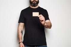 El modelo barbudo confiado del inconformista presenta en algodón superior del verano de la camiseta negra en blanco casual y lle foto de archivo El modelo barbudo confiado del inconformista presenta en algodón superior del verano de la camiseta negra en blanco casual y lle foto de archivo