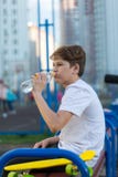 El muchacho lindo deportivo bebe el agua después de jugar a baloncesto en la tierra de deportes Forma de vida sana foto de archivo libre de regalías El muchacho lindo deportivo bebe el agua después de jugar a baloncesto en la tierra de deportes Forma de vida sana foto de archivo libre de regalías