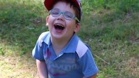 El muchacho lindo feliz en vidrios y casquillo ríe almacen de metraje de vídeo El muchacho lindo feliz en vidrios y casquillo ríe almacen de metraje de vídeo