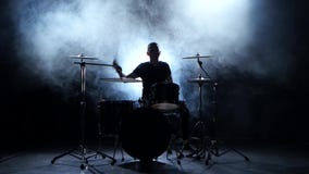 El músico enérgico juega buena música en los tambores Fondo ahumado negro Silueta almacen de metraje de vídeo El músico enérgico juega buena música en los tambores Fondo ahumado negro Silueta almacen de metraje de vídeo