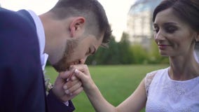 El novio hermoso está besando suavemente la mano hermosa de su novia sonriente de amor en jardín metrajes El novio hermoso está besando suavemente la mano hermosa de su novia sonriente de amor en jardín metrajes