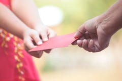 El padre da el dinero en sobre rojo a la muchacha del pequeño niño foto de archivo El padre da el dinero en sobre rojo a la muchacha del pequeño niño foto de archivo