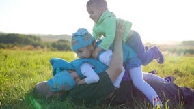 El padre joven feliz con sus niños miente en el césped en el parque Juego de tres niños feliz con su padre Niños almacen de video El padre joven feliz con sus niños miente en el césped en el parque Juego de tres niños feliz con su padre Niños almacen de video