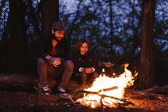 El padre y su peque?o hijo que se sientan en abre una sesi?n el bosque delante de un fuego y las melcochas de la asaci?n en fotografía de archivo El padre y su peque?o hijo que se sientan en abre una sesi?n el bosque delante de un fuego y las melcochas de la asaci?n en fotografía de archivo
