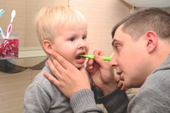 El papá y el hijo cepillan sus dientes en el cuarto de baño Padre Brushing Teeth al niño imagen de archivo El papá y el hijo cepillan sus dientes en el cuarto de baño Padre Brushing Teeth al niño imagen de archivo