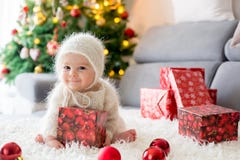 El pequeño bebé en blanco hizo punto el onesie, jugando con y el openin imagen de archivo libre de regalías El pequeño bebé en blanco hizo punto el onesie, jugando con y el openin imagen de archivo libre de regalías