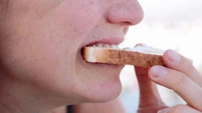 El primer de la boca de la mujer es arranca con los dientes la tostada y la mastica, vista lateral almacen de video El primer de la boca de la mujer es arranca con los dientes la tostada y la mastica, vista lateral almacen de video