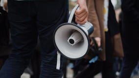 El rebelde pasa en huelga a través de la muchedumbre y de los controles a disposición un megáfono o un altavoz El rebelde pasa en huelga a través de la muchedumbre y de los controles a disposición un megáfono o un altavoz