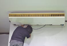 El reparador est? reparando el aire acondicionado en el techo Abra la cubierta del aire acondicionado detr?s del fondo blanco de imágenes de archivo libres de regalías El reparador est? reparando el aire acondicionado en el techo Abra la cubierta del aire acondicionado detr?s del fondo blanco de imágenes de archivo libres de regalías