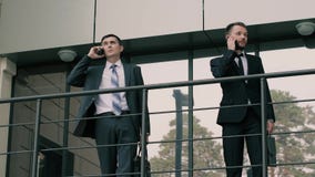 El retrato de dos concentró a los hombres de negocios que hablaban en sus teléfonos sobre trabajo almacen de metraje de vídeo El retrato de dos concentró a los hombres de negocios que hablaban en sus teléfonos sobre trabajo almacen de metraje de vídeo