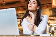 El retrato de la empresaria joven, estudiante, se vistió en la blusa blanca, sentándose en la tabla en café delante del ordenador fotografía de archivo libre de regalías El retrato de la empresaria joven, estudiante, se vistió en la blusa blanca, sentándose en la tabla en café delante del ordenador fotografía de archivo libre de regalías
