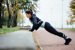 El retrato de la mujer en ropa de deportes, haciendo pectorales de la aptitud ejercita en el parque de la caída, al aire libre Imágenes de archivo libres de regalías El retrato de la mujer en ropa de deportes, haciendo pectorales de la aptitud ejercita en el parque de la caída, al aire libre Imágenes de archivo libres de regalías