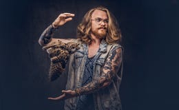 El retrato de un varón tattoed del inconformista del pelirrojo con el pelo lujuriante largo y la barba llena se vistió en una cam foto de archivo El retrato de un varón tattoed del inconformista del pelirrojo con el pelo lujuriante largo y la barba llena se vistió en una cam foto de archivo