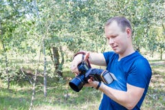 El retrato del fotógrafo de sexo masculino atractivo en el trabajo mira a la cámara Árbol en campo Hombre joven con una cámara de imágenes de archivo libres de regalías El retrato del fotógrafo de sexo masculino atractivo en el trabajo mira a la cámara Árbol en campo Hombre joven con una cámara de imágenes de archivo libres de regalías