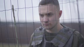 El retrato del militar valiente joven enfocó la colocación detrás de la malla de alambre y guardar el área militar metrajes El retrato del militar valiente joven enfocó la colocación detrás de la malla de alambre y guardar el área militar metrajes