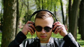 El retrato del primer del estudiante atractivo, hombre pone los auriculares que escucha la música almacen de video El retrato del primer del estudiante atractivo, hombre pone los auriculares que escucha la música almacen de video
