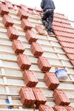El Roofer que trabaja en la estructura de tejado del edificio en la construcción se sienta imagen de archivo El Roofer que trabaja en la estructura de tejado del edificio en la construcción se sienta imagen de archivo