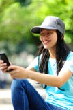 El skater de la mujer se sienta utiliza su teléfono móvil fotos de archivo libres de regalías El skater de la mujer se sienta utiliza su teléfono móvil fotos de archivo libres de regalías