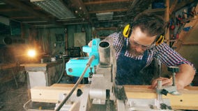 El tablero de madera está consiguiendo cortado mecánicamente por un trabajador de sexo masculino Artesano que trabaja en carpinte almacen de video El tablero de madera está consiguiendo cortado mecánicamente por un trabajador de sexo masculino Artesano que trabaja en carpinte almacen de video