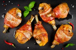 El tocino envolvió las piernas de pollo en un fondo negro fotografía de archivo libre de regalías El tocino envolvió las piernas de pollo en un fondo negro fotografía de archivo libre de regalías