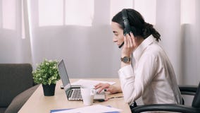El trabajador de sexo femenino del centro de atención telefónica contesta a llamada de cliente en oficina El trabajador de sexo femenino del centro de atención telefónica contesta a llamada de cliente en oficina