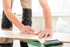El trabajador de sexo masculino aplica marcas al tablero para cortar con un electrofret vio instalación del nuevo suelo laminado imagen de archivo El trabajador de sexo masculino aplica marcas al tablero para cortar con un electrofret vio instalación del nuevo suelo laminado imagen de archivo