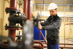 El trabajador mecánico cierra la válvula de puerta de la tubería en fábrica industrial del gas y del aceite imagen de archivo libre de regalías El trabajador mecánico cierra la válvula de puerta de la tubería en fábrica industrial del gas y del aceite imagen de archivo libre de regalías