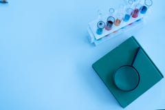 El tubo de cristal de la ciencia, muchos tubos de ensayo que contienen líquidos coloridos, una lupa y un libro en la tabla del la imagenes de archivo El tubo de cristal de la ciencia, muchos tubos de ensayo que contienen líquidos coloridos, una lupa y un libro en la tabla del la imagenes de archivo
