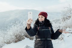 El turista femenino sonriente vistió caliente tomando un selfie en una c nevosa imágenes de archivo libres de regalías El turista femenino sonriente vistió caliente tomando un selfie en una c nevosa imágenes de archivo libres de regalías