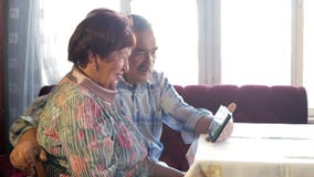 An elderly couple communicates with their grandchild by video linking the tablet. A man and a woman are talking to stock footage An elderly couple communicates with their grandchild by video linking the tablet. A man and a woman are talking to stock footage
