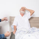 Elderly man with strong headache while sitting in bed Stock Photo Elderly man with strong headache while sitting in bed Stock Photo
