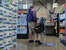 Elderly man wearing a face mask while waiting in line at a QFC grocery store, minding the social distancing signs