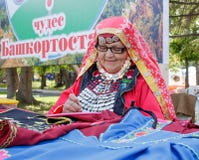 An elderly woman in Bashkir clothes embroiders a crochet pattern. Traditional national holiday Sabantuy in the city park royalty free stock photos An elderly woman in Bashkir clothes embroiders a crochet pattern. Traditional national holiday Sabantuy in the city park royalty free stock photos